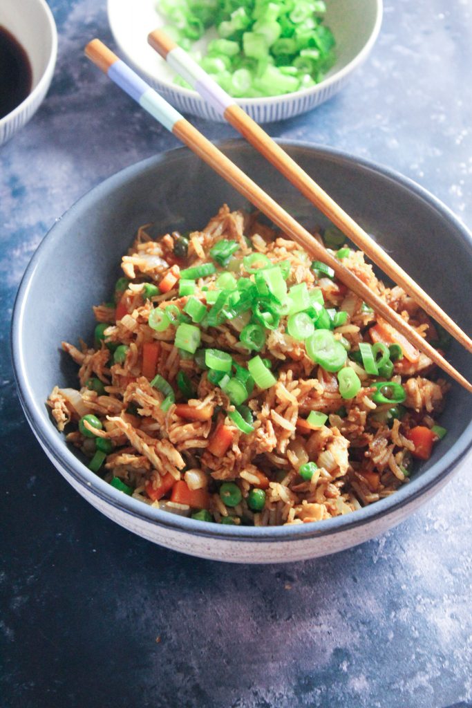 Bowl of chicken fried rice with a pair of chopsticks. 