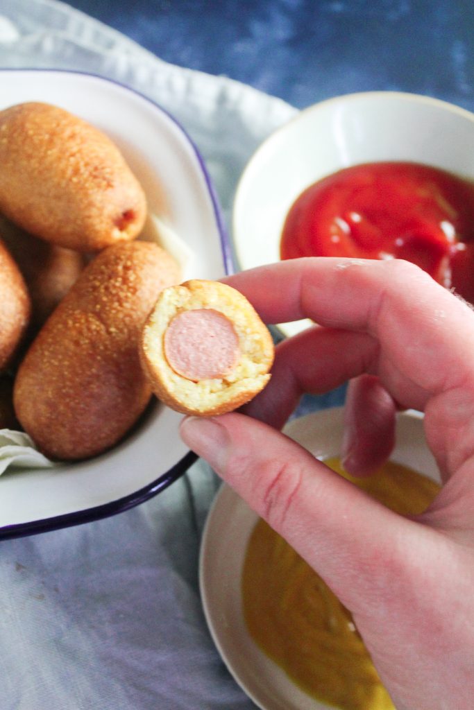 Close up of a mini corn dog with a bite taken out.